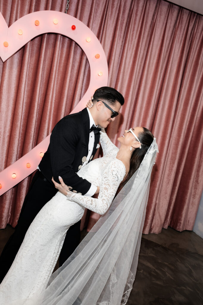Couple posing in front of the pink heart at Sure Thing Chapel in Las Vegas.