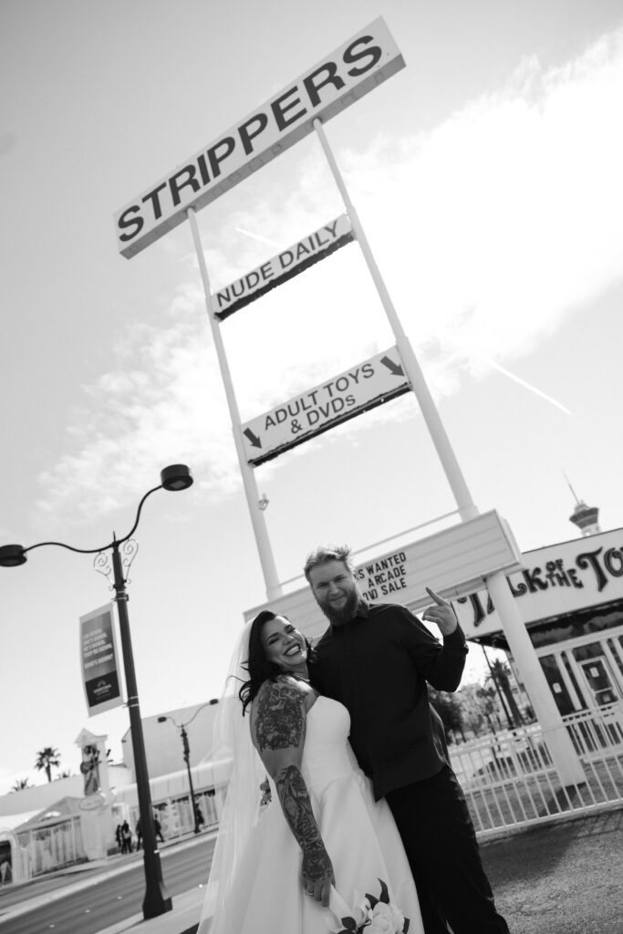 Bride and groom portraits with the strippers sign in the background