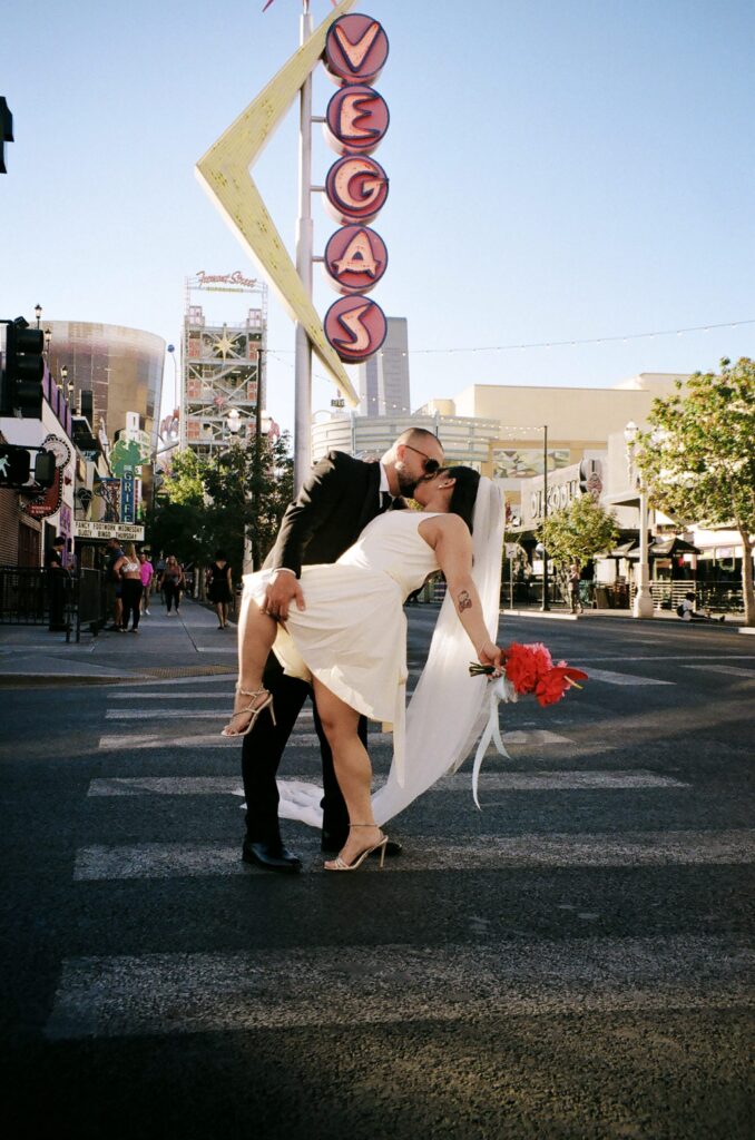 Bride and groom walking down Fremont Street in Vegas for their portraits on film