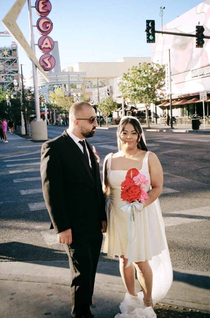 Bride and groom walking down Fremont Street in Vegas for their portraits on film