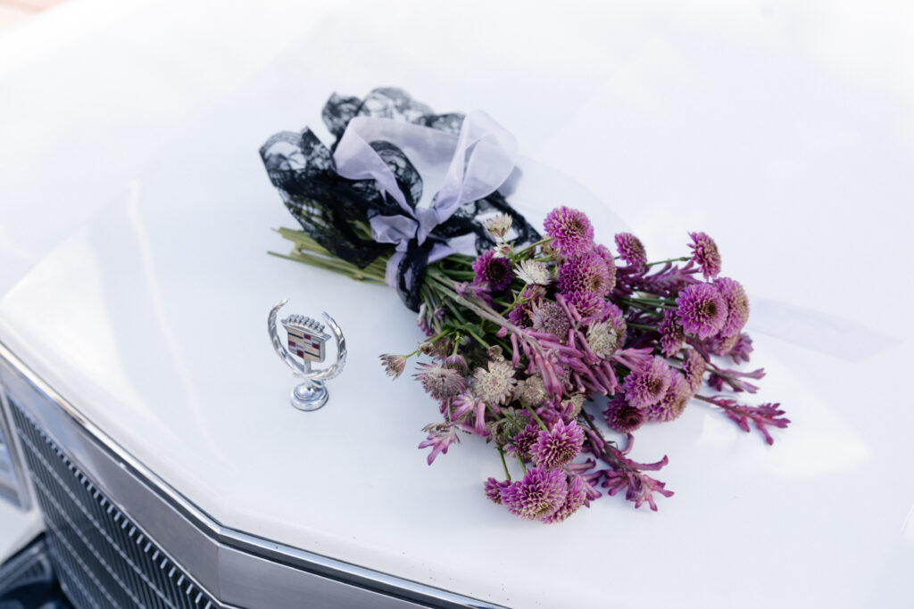 Purple wedding bouquet on a vintage car