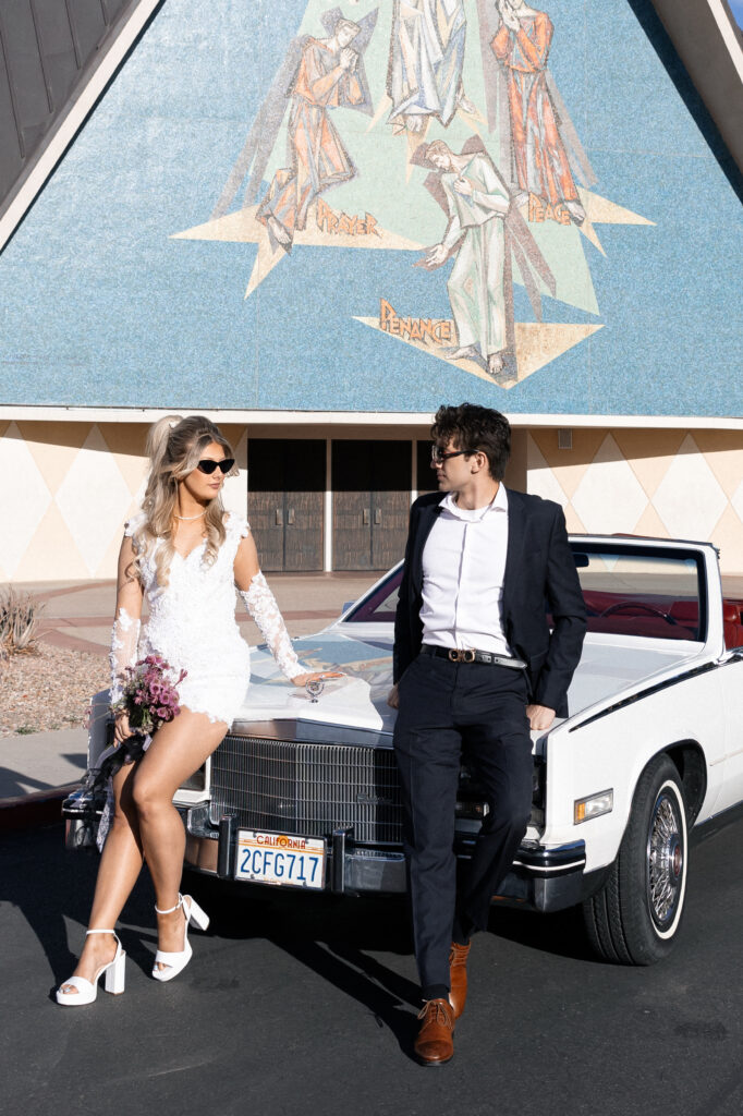 Bride and groom posing with a vintage car