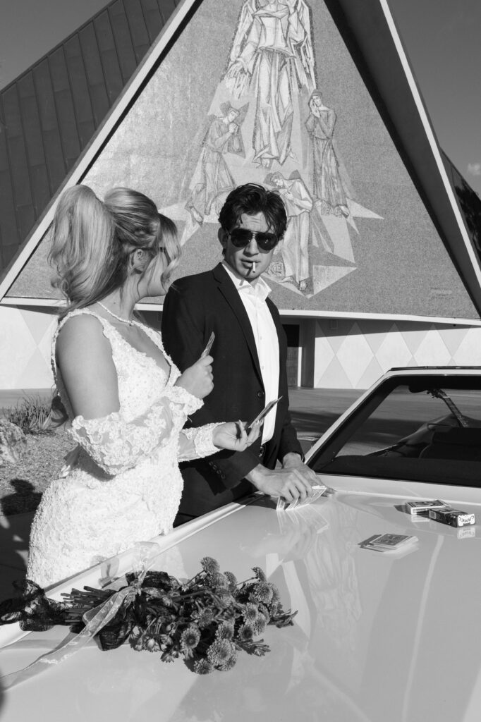 Bride and groom posing with a vintage car