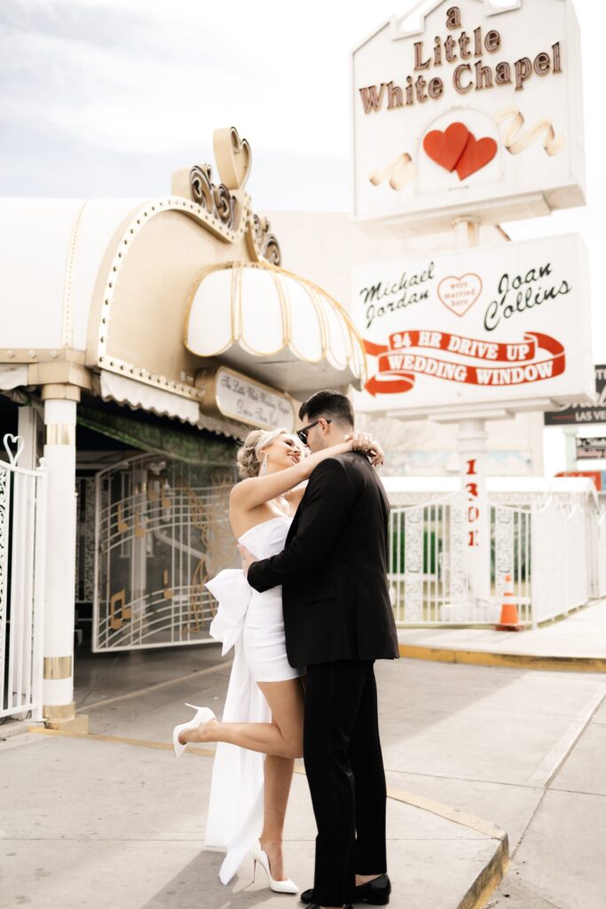 Bride and groom posing for photos in front of The Little White Chapel during their elopement in Vegas
