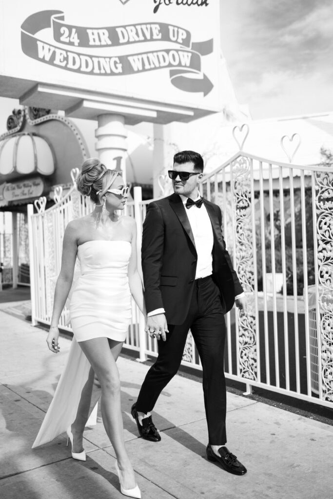 Black and white photo of the bride and groom walking by The Little White Chapel during their elopement in Vegas