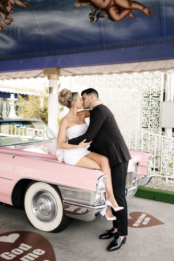 Bride and groom kissing on the Pink Cadillac at The Little White Chapel for their elopement in Vegas