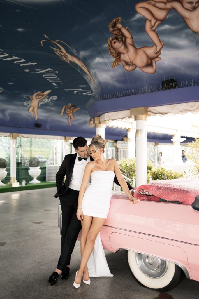 Bride and groom posing with the Pink Cadillac at The Little White Chapel