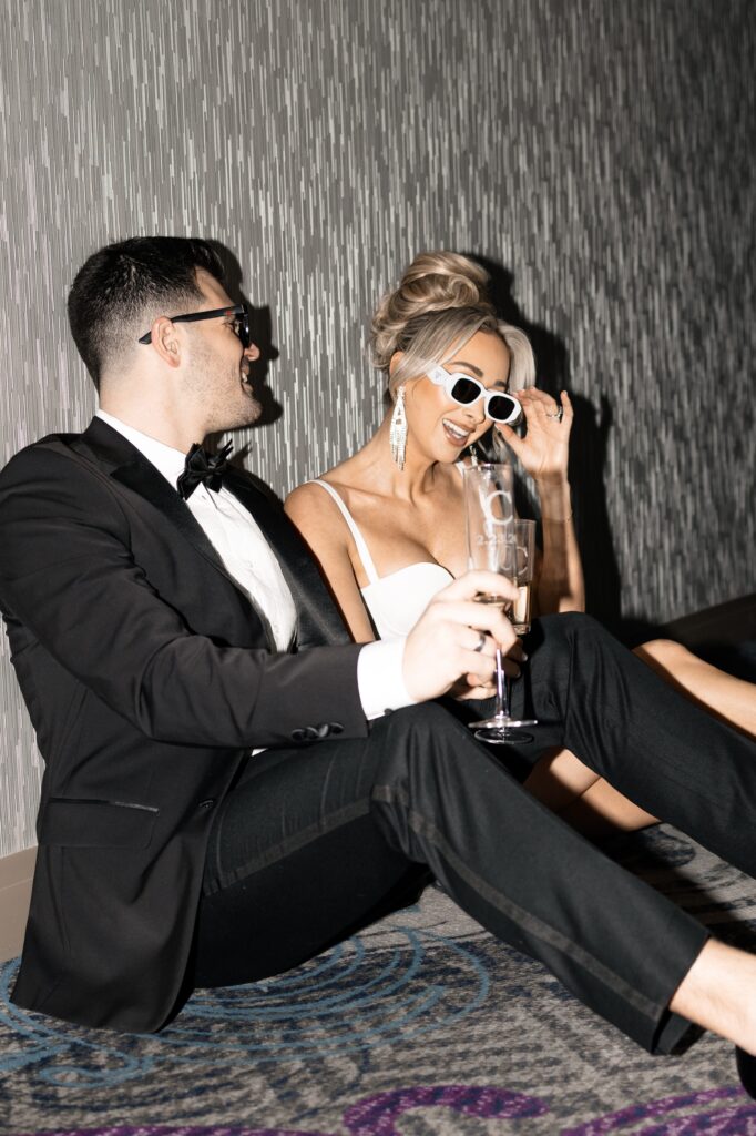 Flash photos of a bride and groom sitting in the hallway of The Cosmopolitan Hotel in Las Vegas wearing sunglasses with champagne.
