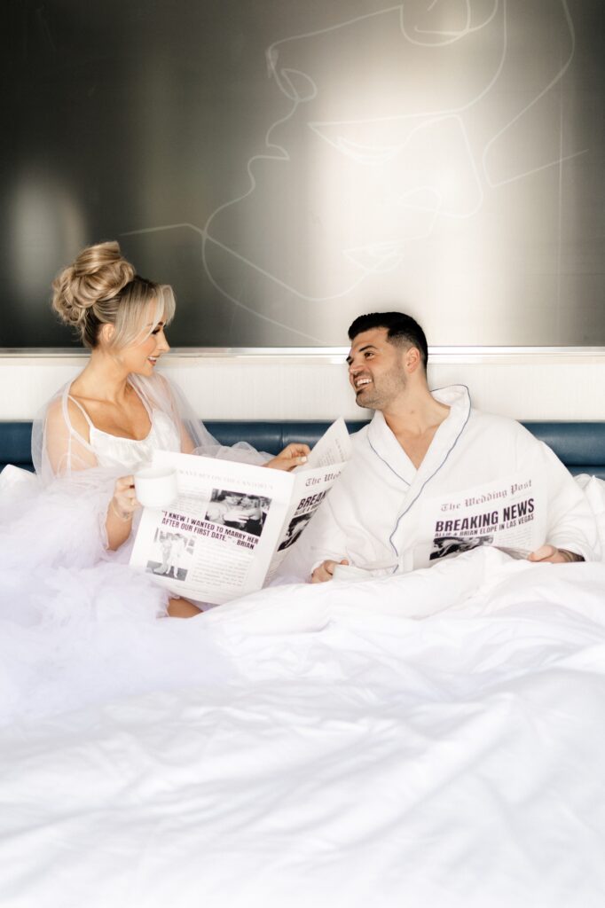 Bride and groom laying in a bed with a custom "Breaking News" elopement announcement newspaper