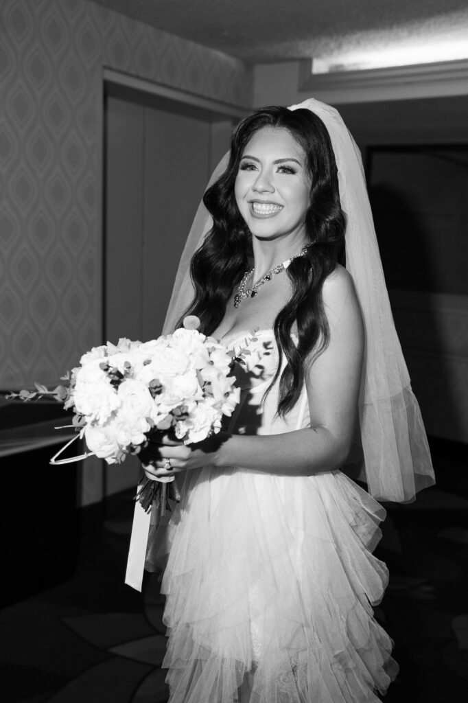 Black and white photo of a bride in her wedding dress holding her bouquet