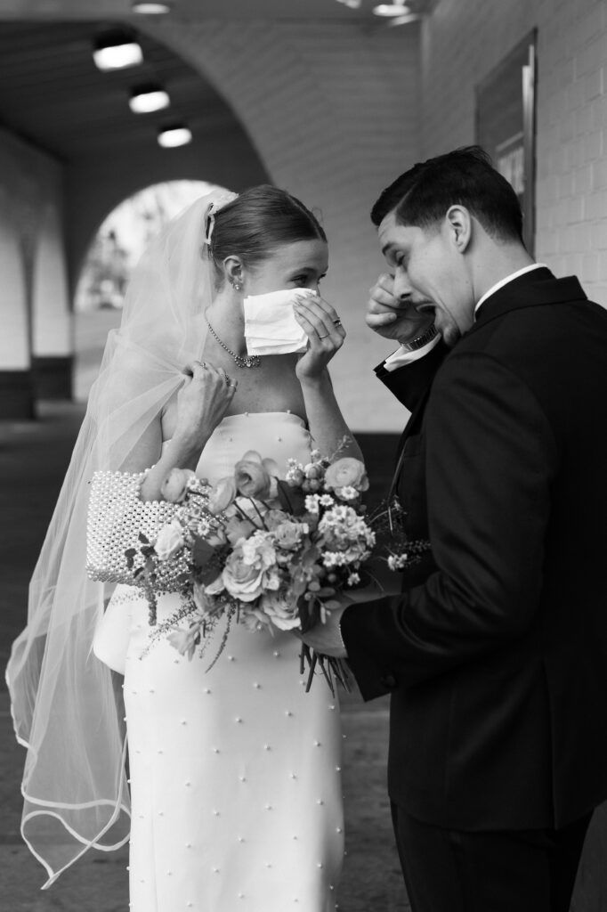 Black and white photo of a bride and groom getting emotional during their first looks at the corner of El Cortez Hotel and Fremont Street in Las Vegas