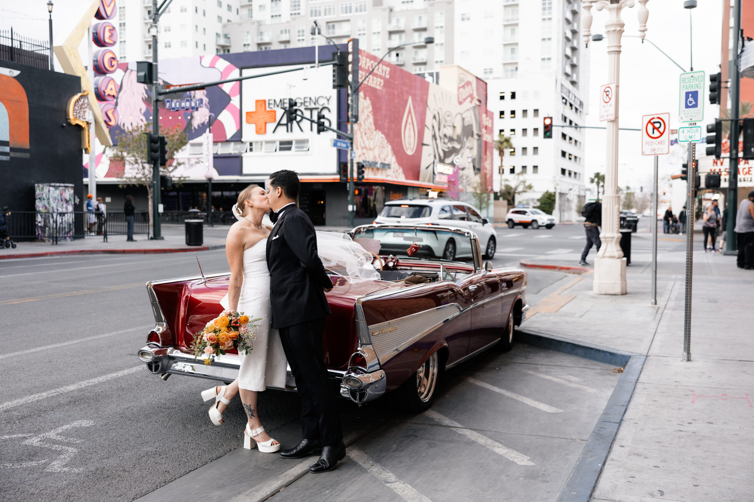Bride and groom posing with a vintage red Chevrolet car for their Las Vegas wedding elopement