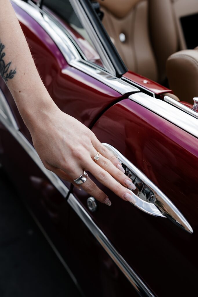 Close up shot of a bride wearing her wedding ring as she goes to open a car door
