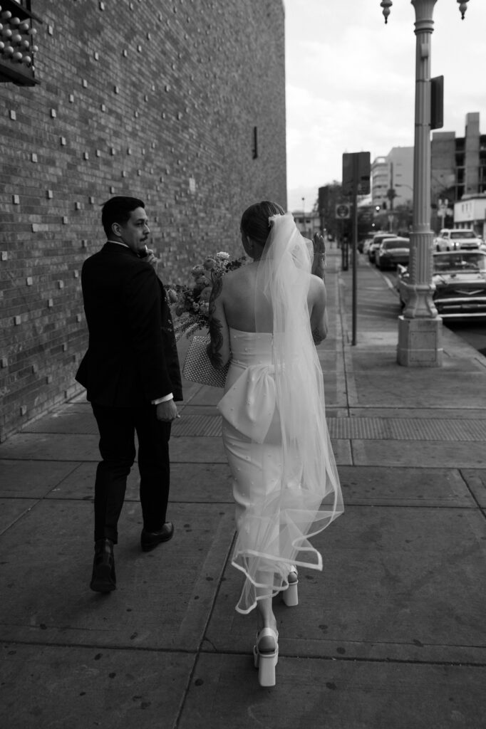Black and white photo of a bride and groom walking down Fremont Street in Las Vegas