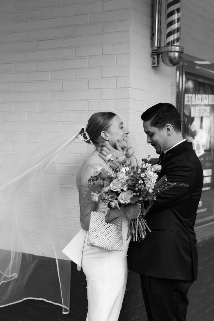 Black and white photo of a groom admiring his bride during their first looks