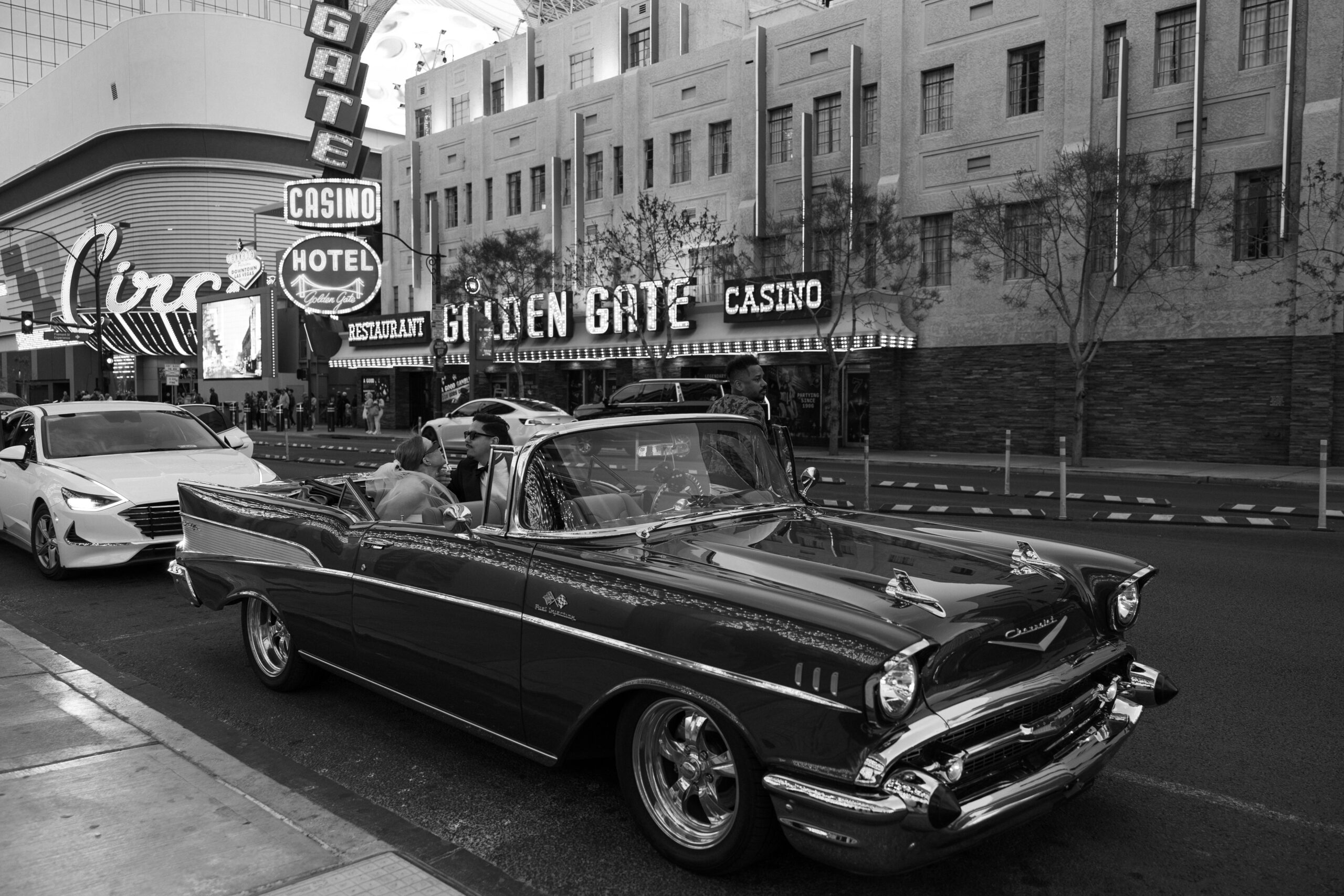 Black and white photo of a bride and groom sitting in a classic Chevrolet in front of Golden Gate Casino in Vegas. 