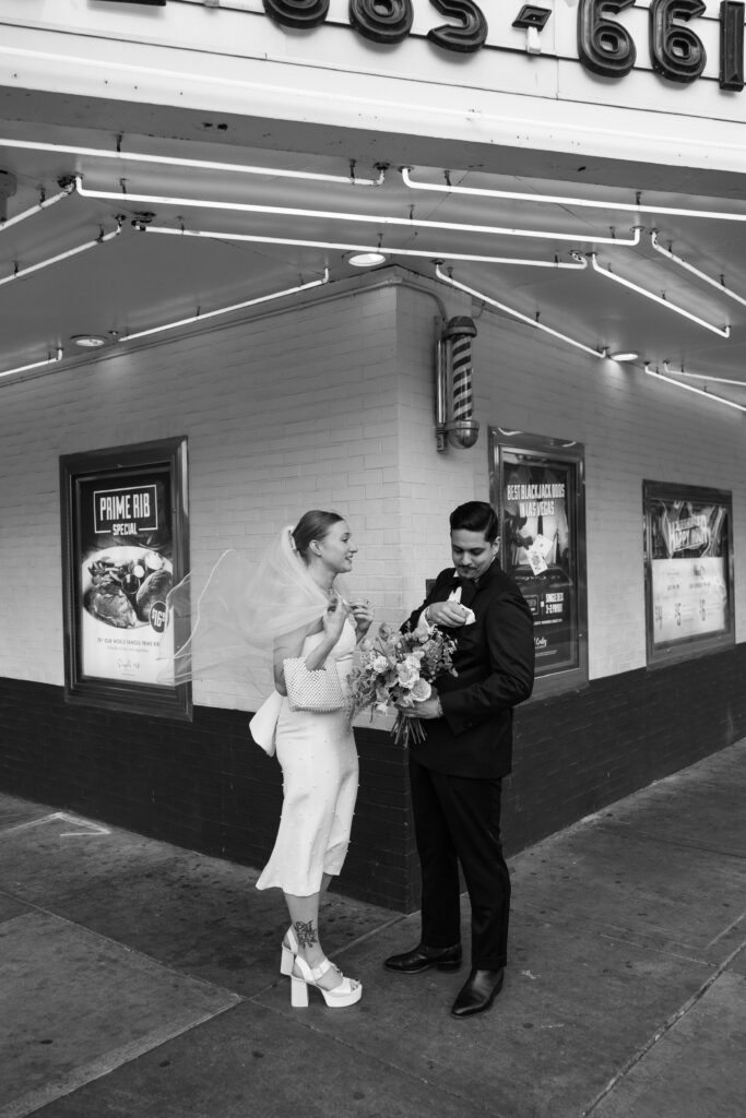 Black and white photo of a bride and groom, during their first looks at the corner of El Cortez Hotel and Fremont Street in Las Vegas