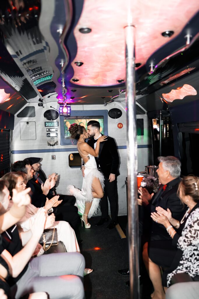 Bride and groom kissing on the party bus