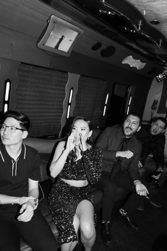 Wedding guests cheering on bride and groom as they enter the party bus