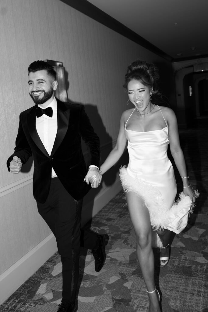 Black and white photo of bride and groom running down the hallway at Palazzo Hotel in Las Vegas