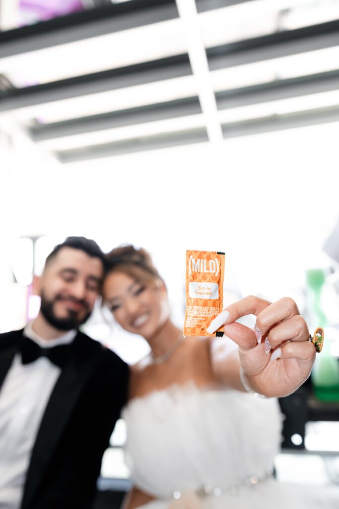 Bride and groom holding up a taco bell sauce packet that says "yes to forever" during their Taco Bell Las Vegas wedding