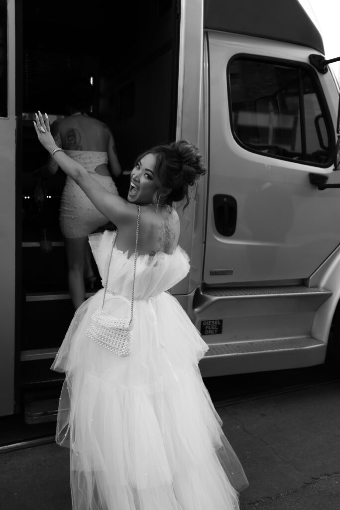 Black and white photo of a bride getting into her party bus