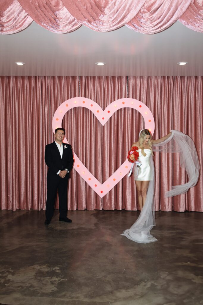 Bride and grooms portraits at Sure Thing Chapel in front of the pink neon heart