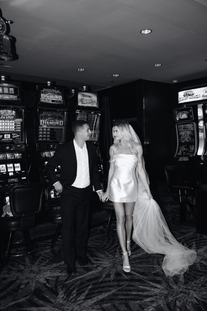 Black and white photo of a bride and groom walking inside Fremont Casino