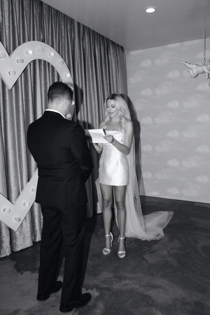 Black and white photo of a bride reading her vows to her groom during their intimate Sure Thing Chapel elopement ceremony