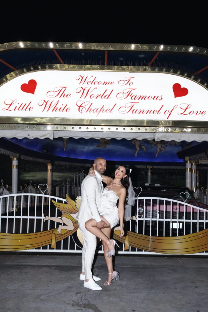 Bride and groom posing in front of Little White Wedding Chapels Tunnel of Love entrance