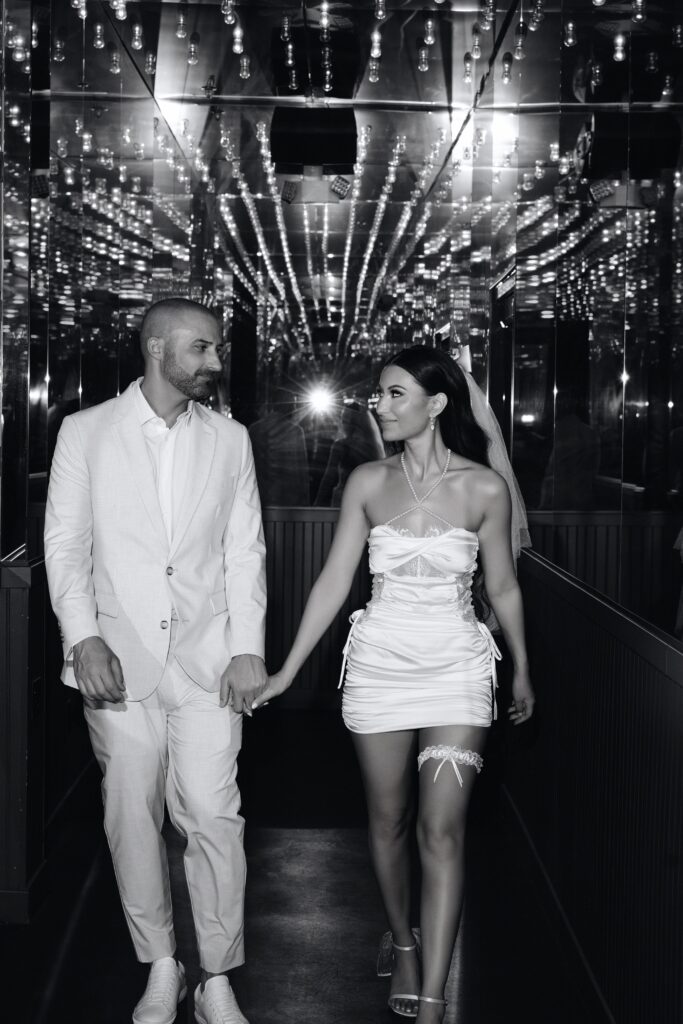 Black and white photo of a bride and groom walking down a lit hallway in Las Vegas.