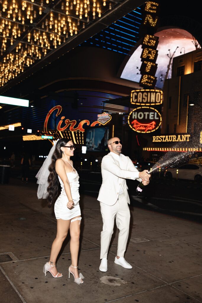 Bride and groom popping champagne on Fremont Street during their Las Vegas elopement