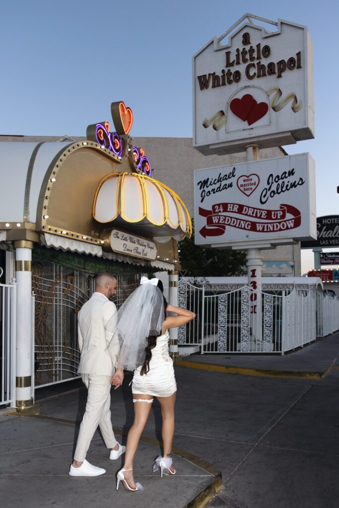 Bride and groom walking in front of Little White Wedding Chapel in Las Vegas