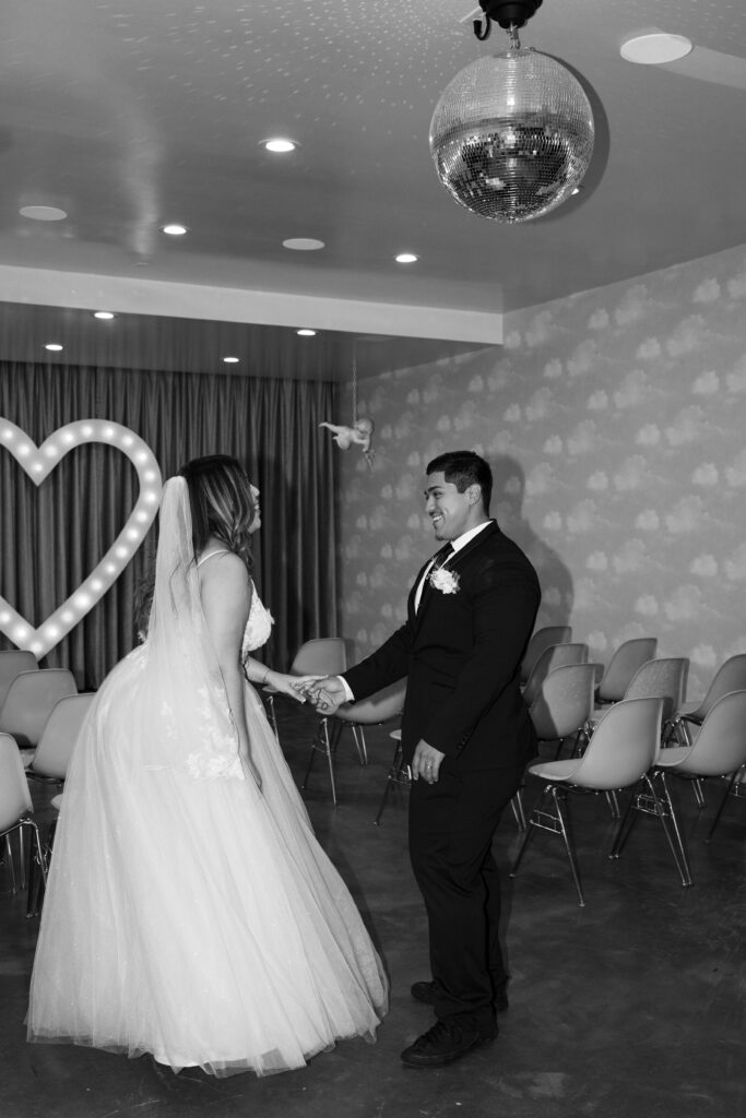 Black and white photo of a bride and groom dancing underneath a disco ball at Sure Thing Chapel