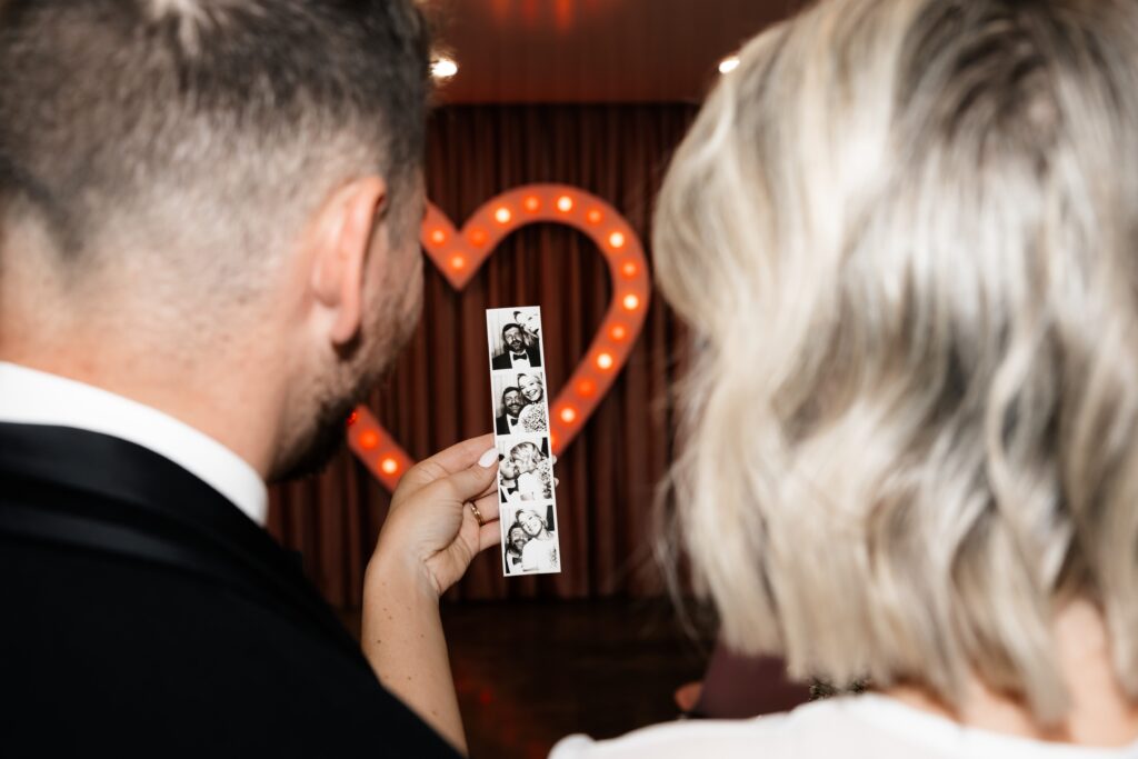 Bride and groom looking at their photo strip from the analog photog booth at Sure Thing Chapel