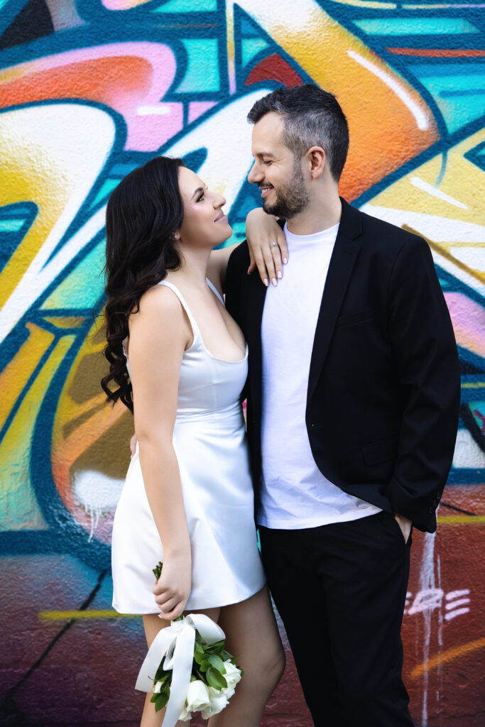 Bride and groom posing for photos in front of a colorful mural in Las Vegas