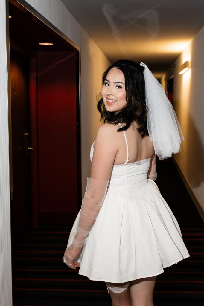 Flash photo of a bride at the D Hotel & Casino in Las Vegas while wearing a short dress, short veil, and mesh sleeves. 