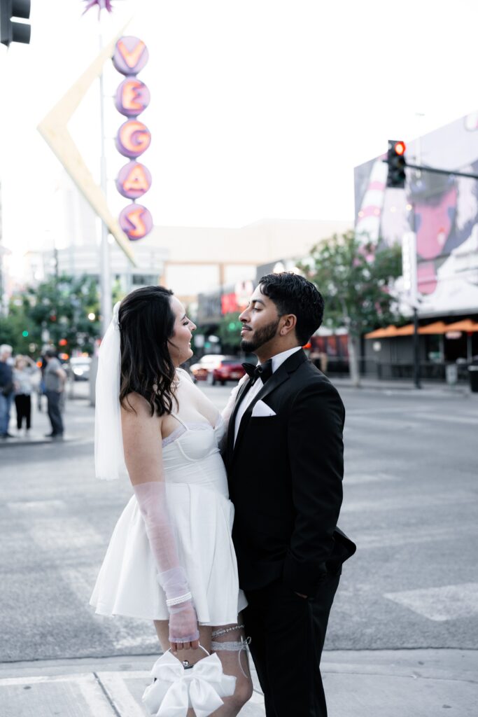 Bride and groom posing for portraits on Fremont Street in front of the iconic vintage Vegas sign