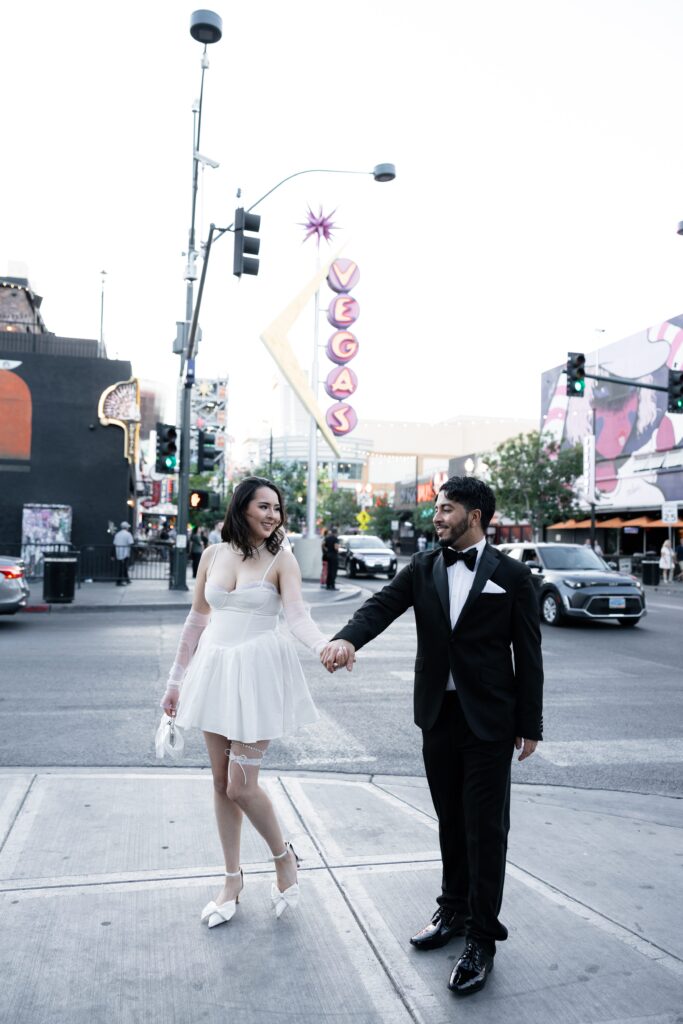 Bride and groom posing for portraits on Fremont Street in front of the iconic vintage Vegas sign