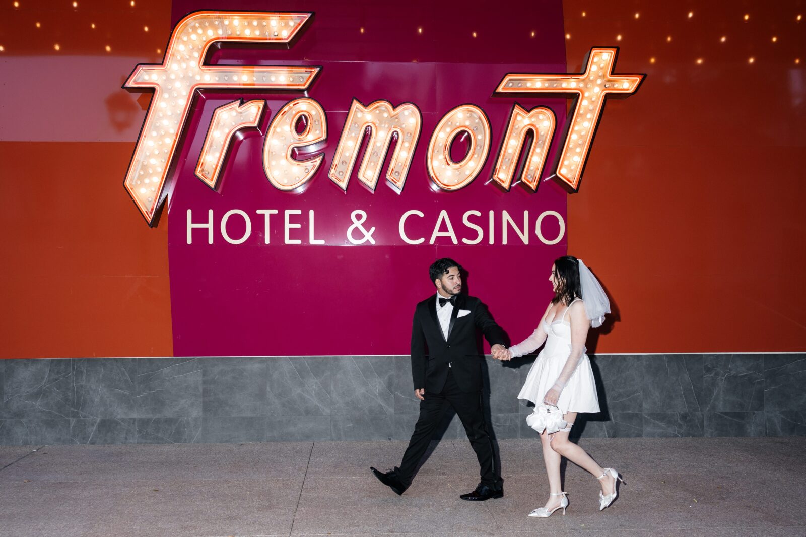 Bride and groom walking in front of Fremont Hotel & Casino sign