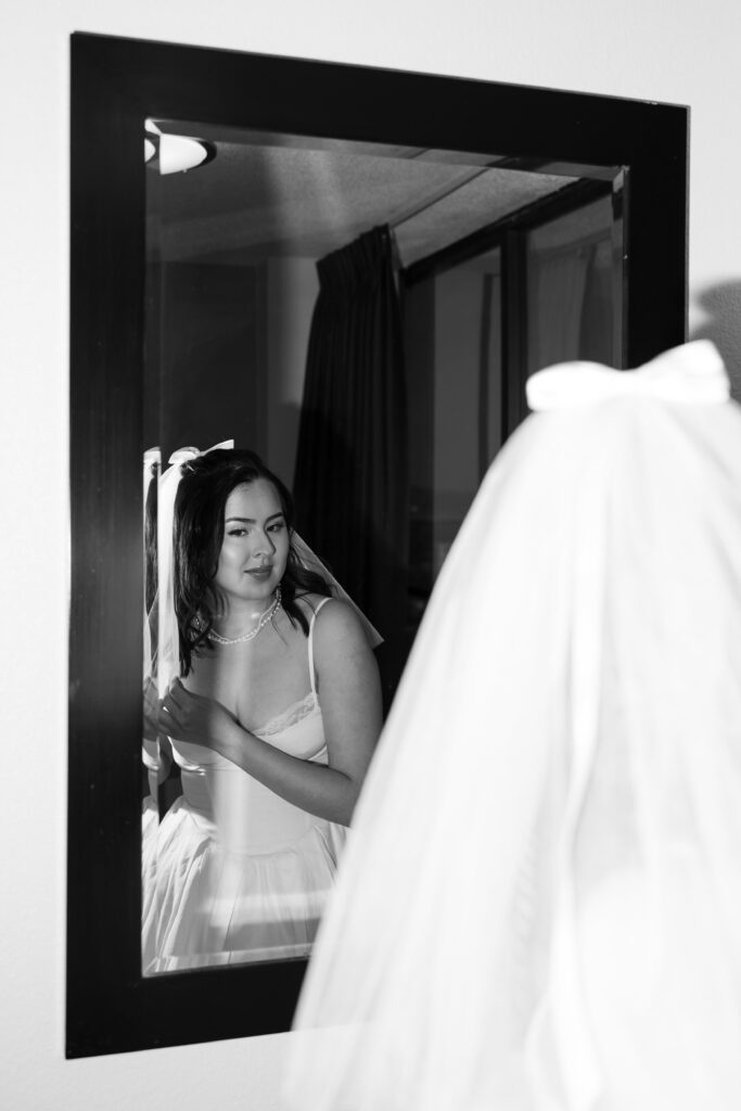 Black and white photo of a bride and groom getting ready in her hotel room