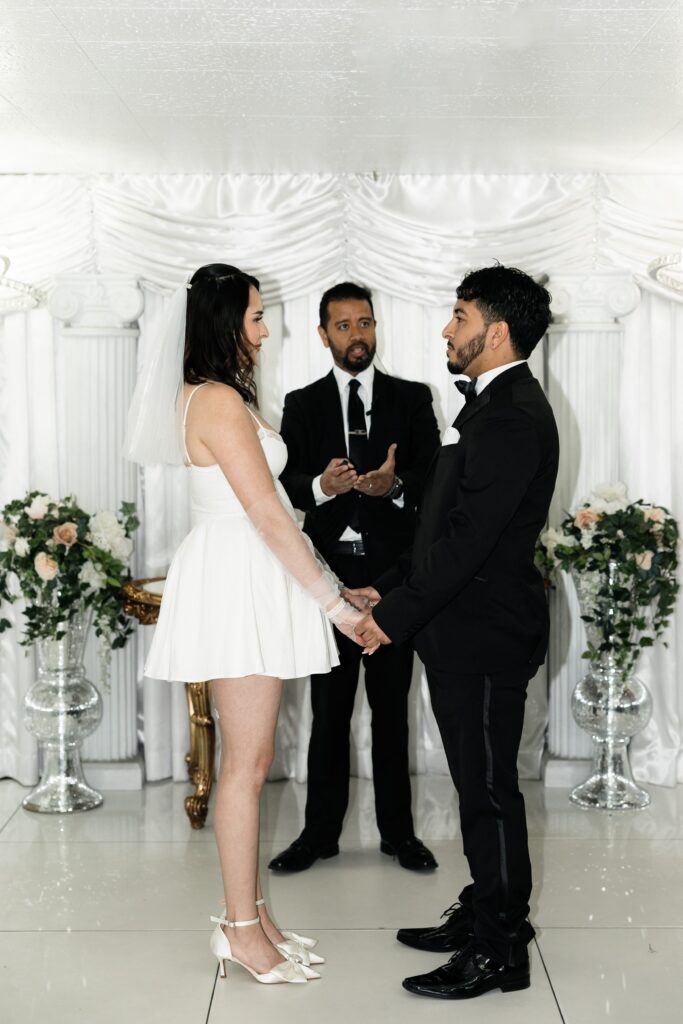 Bride and groom holding hands at the altar during their Little White Wedding Chapel ceremony