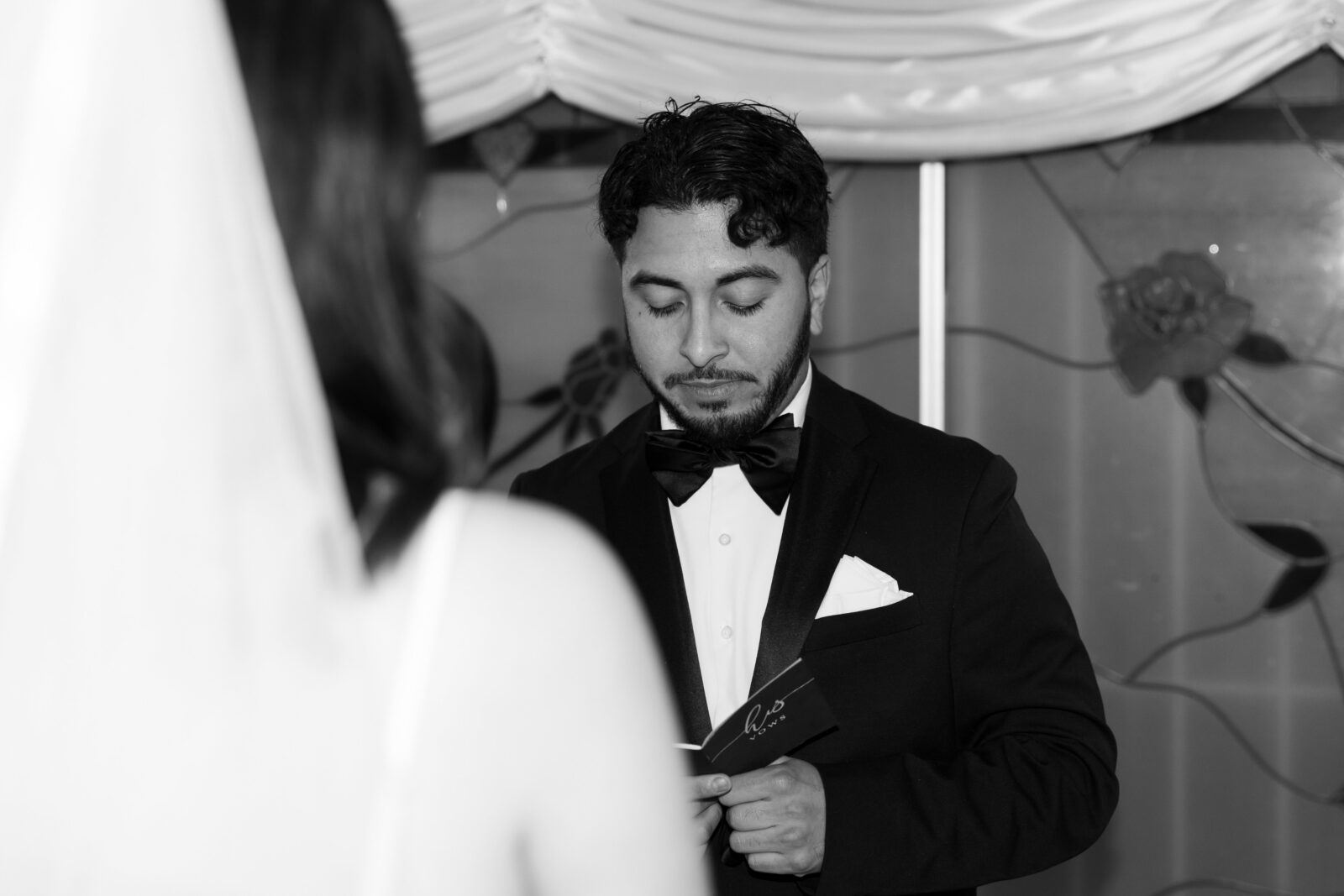 Black and white photo of a groom reading his vows to his bride during their Little White Wedding Chapel ceremony