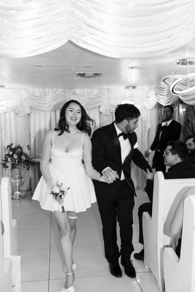 Black and white photo of a bride and groom walking back down the aisle together after their Little White Wedding Chapel ceremony