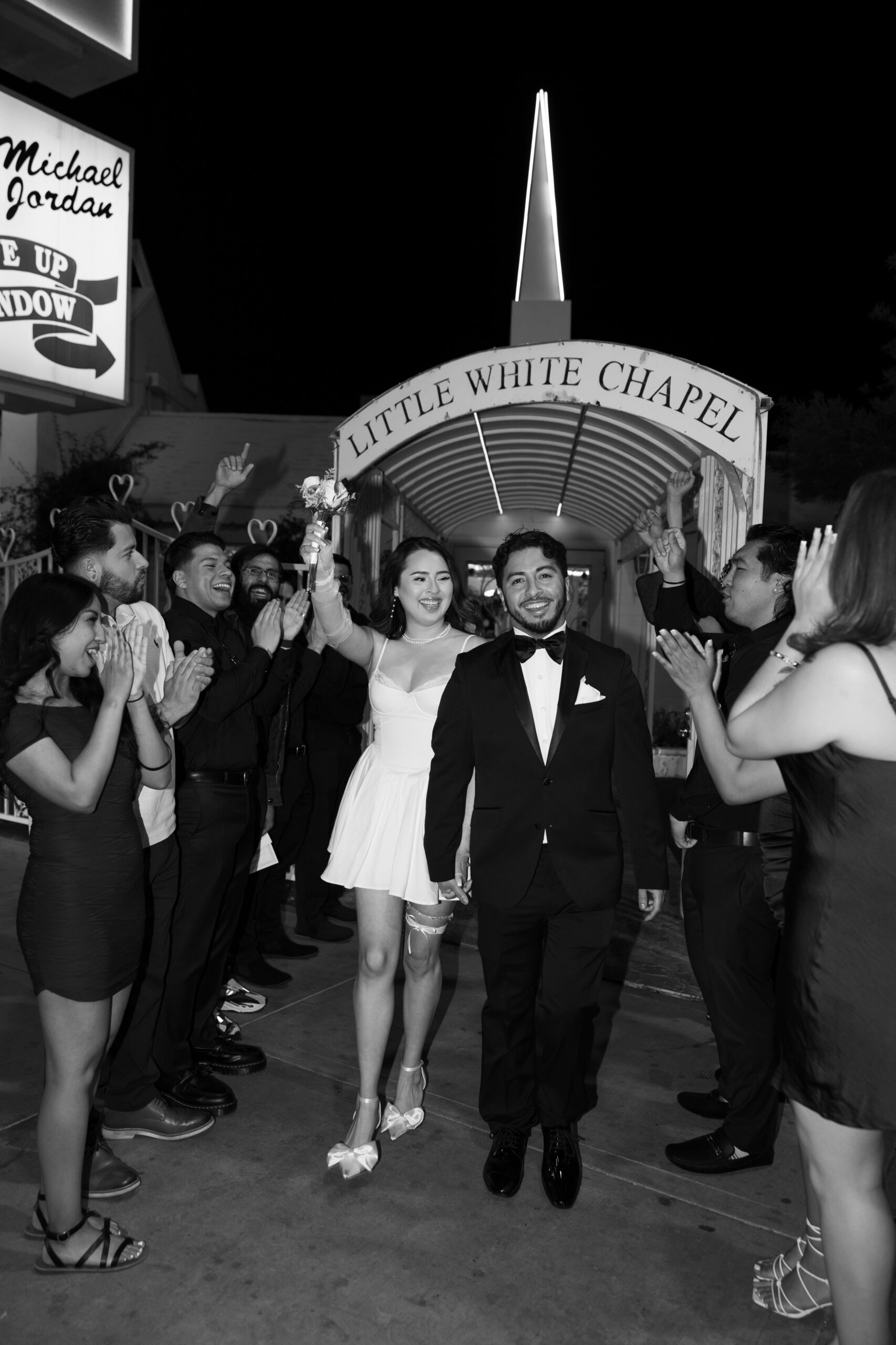 Black and white photo of a bride and groom exiting their Little White Chapel elopement