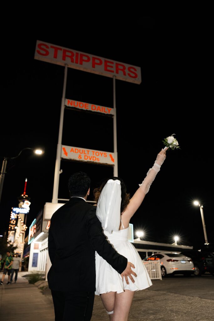 Bride and groom posing in front of the strippers sign in downtown Las Vegas