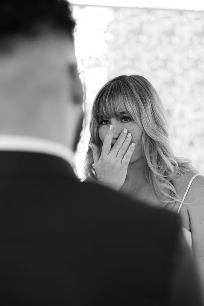 Black and white photo of a bride getting emotional as her groom reads his vows to her during their Las Vegas elopement in the Gazebo at Little White Wedding Chapel