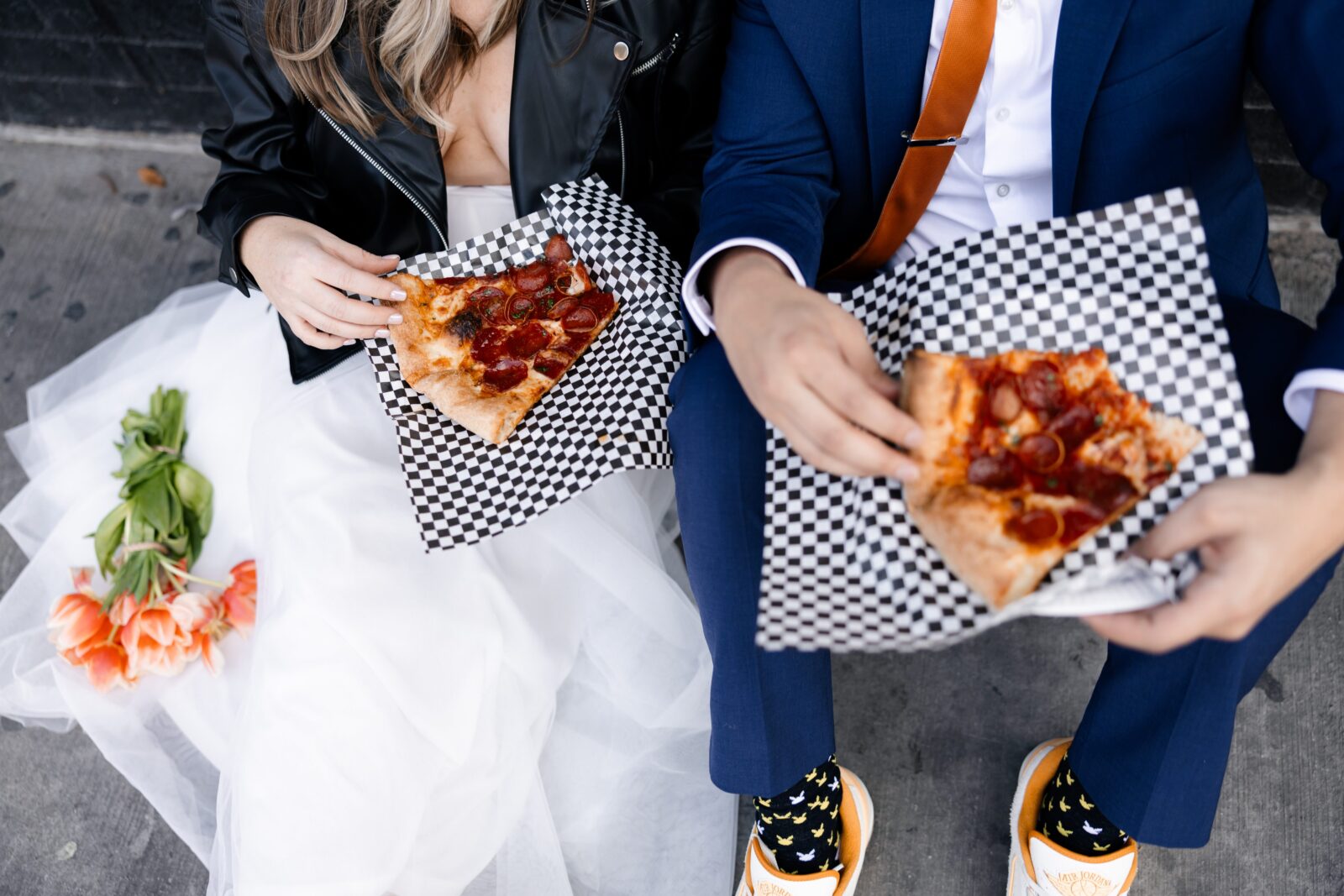 Bride and groom sitting on the sidewalk and eating pizza during their Las Vegas elopement