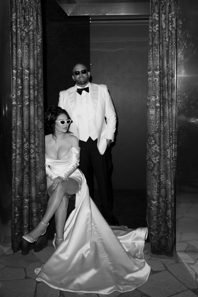 Black and white photo of a bride and groom sitting in a photo booth