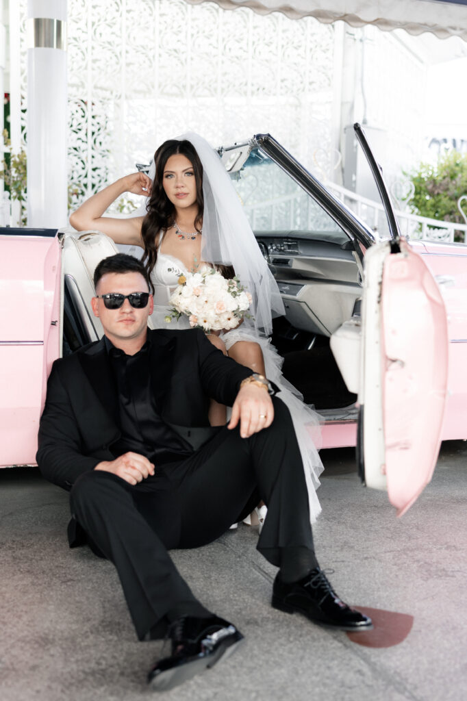 Bride and groom posing for photos inside of The Little White Wedding Chapels Pink Cadillac